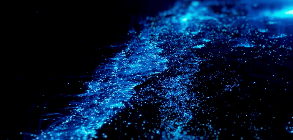 Bioluminescent blue waves glowing in the dark sea.