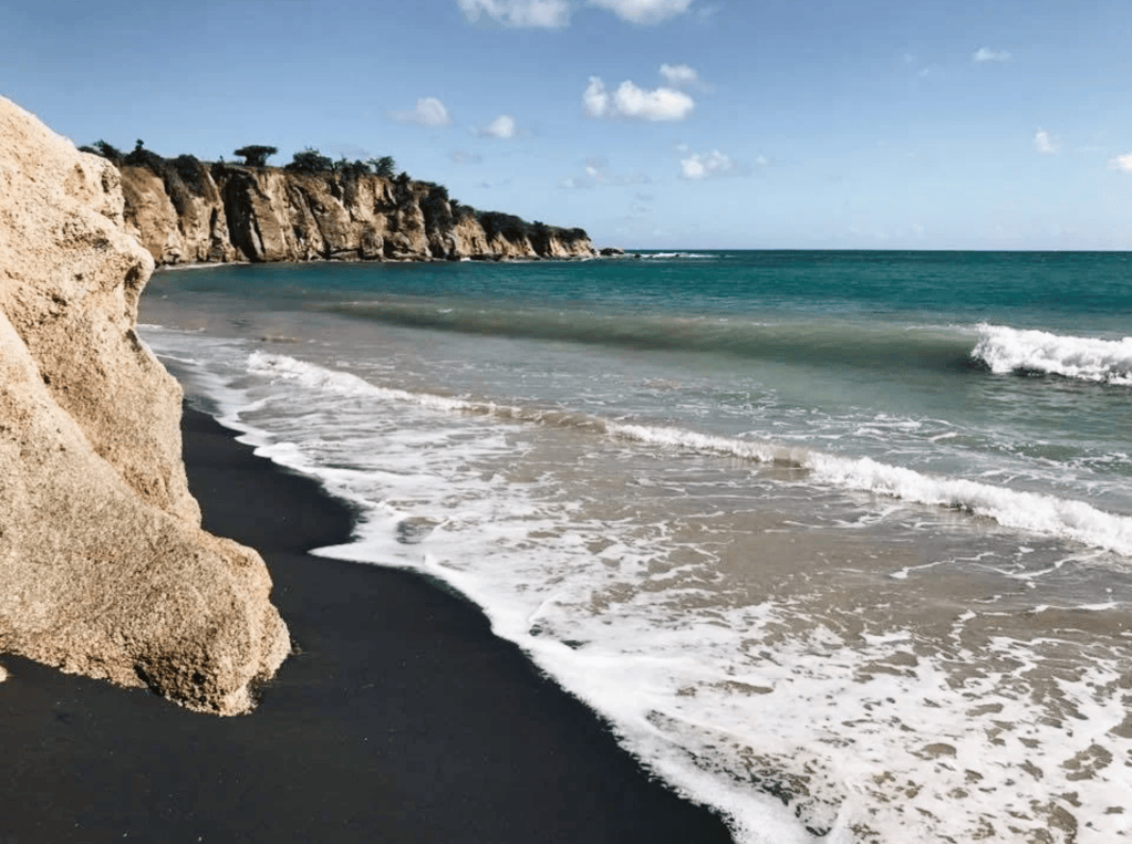 Rocky coastline with waves and blue sky.